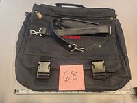 Front view of black computer bag with shoulder strap showing buckles and KBR embroidery
