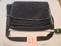 Front view of black Express messenger bag with measuring tape showing width ~16"