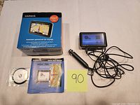 All lot contents laid out: GPS unit powered on, power cable, manual, disc, box