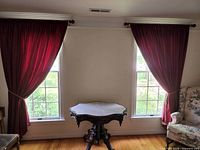 Pair of red lined curtains hung on window with tiebacks
