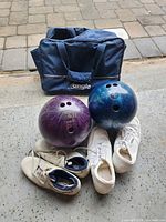 Lot overview showing two bowling balls, two pairs shoes, navy Angle bag