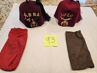 Two burgundy Shriners fezzes with storage bags overview