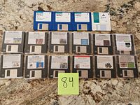 All nineteen 3.5-inch floppy disks laid out on countertop showing labels and disk fronts