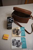 Camera, case, two manuals and sealed film roll displayed