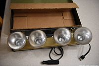 Light bar with four reflector bulbs, handle and cord on countertop