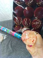 All items together: stress ball in hand, pack of red ornaments, wrapping paper roll