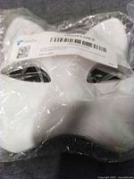 Front view of sealed stack of white cat masks showing shape and barcode label
