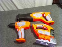 All three toy power tools laid out: drill, reciprocating saw, circular saw