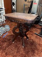 full view of side table showing wood pedestal base, marble top, casters