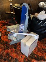 Lot overview showing bath lift chair components, boxed toilet seat, grab bar, reacher, and blood pressure monitor