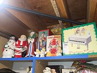Shelf view showing boxed Christmas Piano, light-up figures, ceramic Santa, and angels