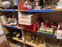 Shelf showing multiple ornament boxes, figurines, candles