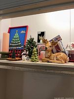 Shelf with deer figurine, mini tree, candles, framed Christmas tree art, small snowman, candle holders, butterfly figurine