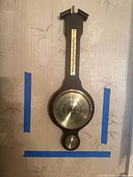 Full view of wall-mounted Tradition weather station showing thermometer, barometer, hygrometer on wood plaque