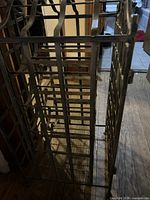 Side view of metal wine rack, showing lattice bottle supports and gate