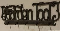 Front view of cast iron "Garden Tools" hook rack mounted on wall