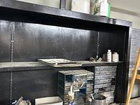 Front view of black painted metal garage cabinet with shelves