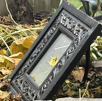 Front angled view of the ornate rectangular wood-framed mirror showing carved detail and weathered finish
