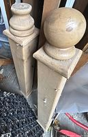 Two unfinished wood posts side by side showing square shafts and different finials