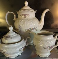Front view of teapot, creamer and covered sugar bowl showing pattern and shape