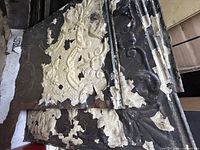 Stack of distressed ornate metal ceiling panels showing pattern and paint loss