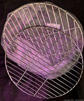 Both round chrome grill grates stacked, one in plastic sleeve
