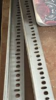 Two slotted steel strut rails showing slot pattern and finish