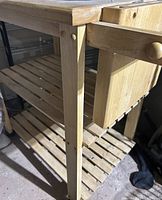 Side view of cart showing frame, drawer, two slatted shelves and wheel mount