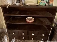 Front view of wooden cabinet showing shelves, drawers and accessories on and inside