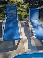 Two blue mesh pool lounge chairs beside pool