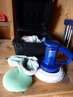 Blue Simoniz polisher with wool pad, foam pad, microfiber bonnets beside black case