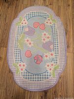 Oval rug laid on wood floor showing full design and colors