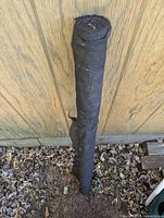 Full view of black landscape fabric roll leaning against wall