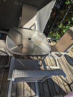 Square glass patio table with surrounding sling chairs
