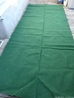 Full view of dark green outdoor rug laid flat showing size and fold lines