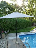 Umbrella fully open beside pool showing canopy and base