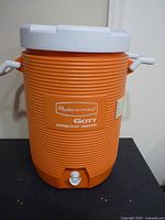 Front view of orange Rubbermaid Gott cooler showing lid, handles, spigot and branding