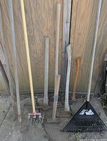 Multiple yard hand tools leaning against wall