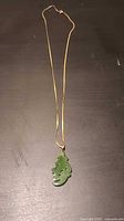 Full view of gold chain with green stone pendant