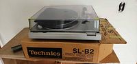 Turntable on top of original Technics SL-B2 box showing complete unit with dust cover