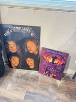Both wooden Metallica posters leaning against wall