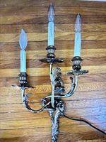 Front view of bronze three-arm wall sconce showing full structure and wiring