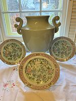 Overall view: three plates on stands flanking large green handled vase