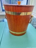 Front view showing teak grain, brass bands and handles