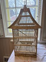 Full view of wooden pagoda birdcage on table