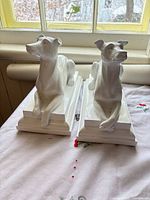 Front view of two white resin greyhound statues on bases