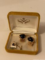 open presentation box showing cufflinks, tie tack and tag