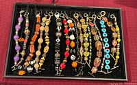 Tray of twenty assorted beaded bracelets lined side by side