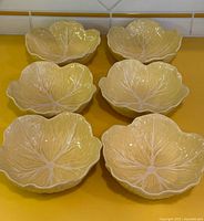 Six yellow cabbage-leaf bowls arranged on countertop