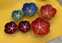 Six multicolour cabbage bowls displayed on yellow surface